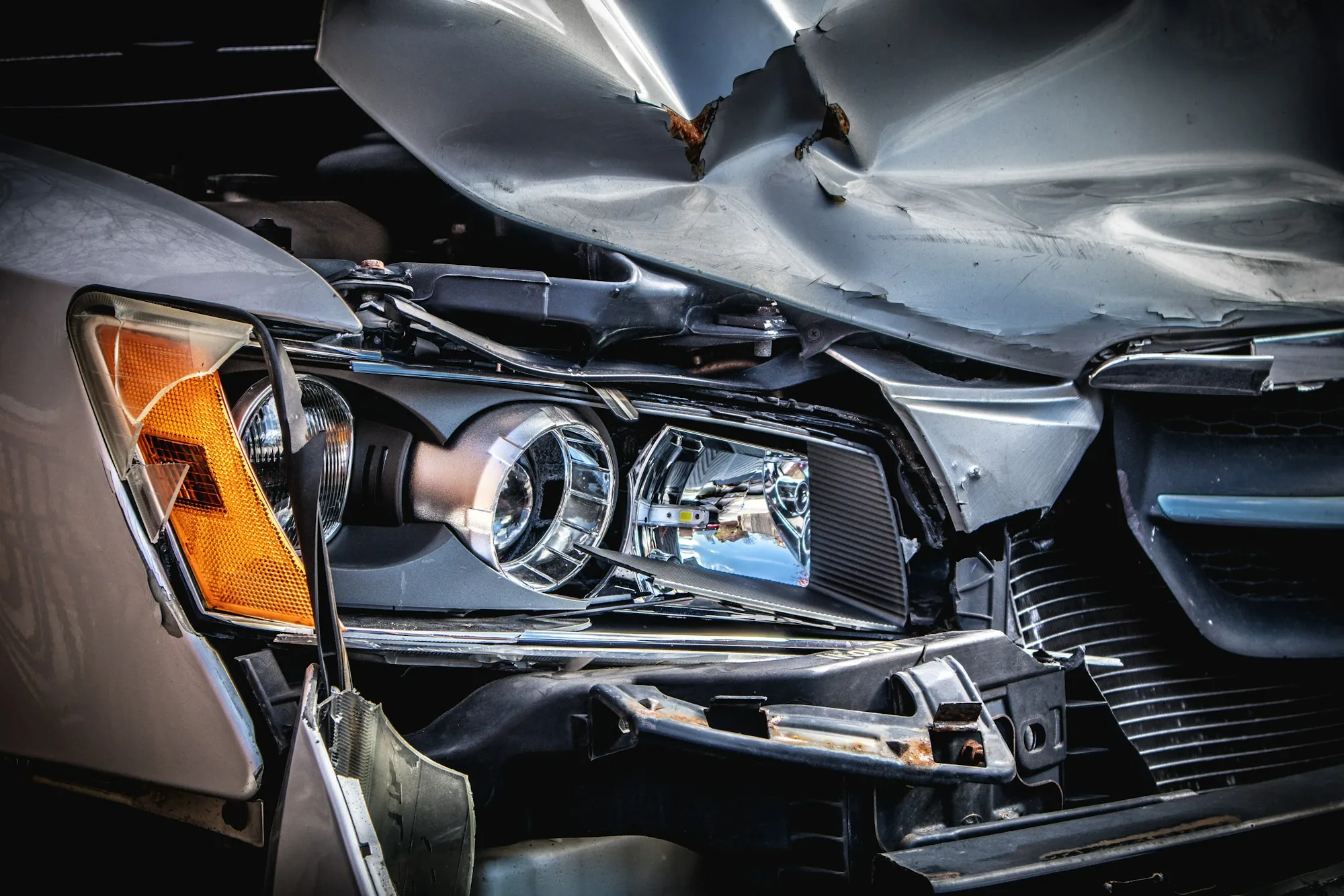 Close-up of a car's crushed front end and broken headlight